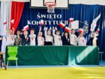 Uczniowie za stołem machają flagami